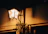 A softly lit hanging porch lantern casting warm light over a wooden porch at dusk.