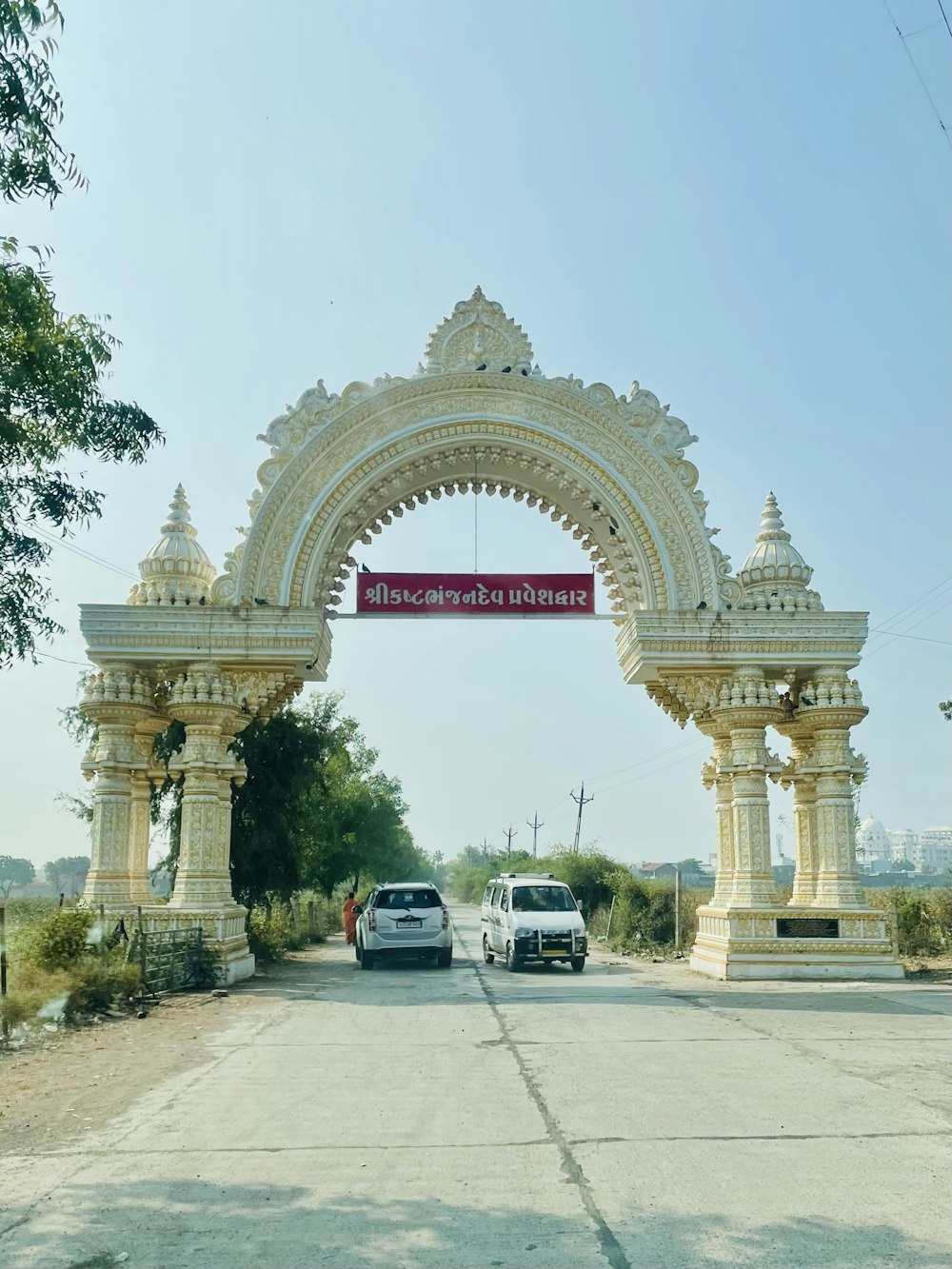 a white car driving under an archway on a road