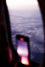 A happy traveler using a smartphone to book a flight with a scenic mountain backdrop.