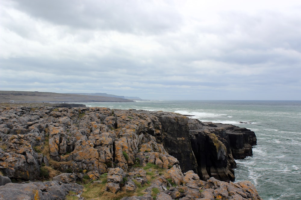 a rocky cliff with a body of water in the background