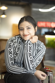 Close-up of the doctor smiling warmly, with a deep teal and blue gradient background accented by white geometric wave lines.