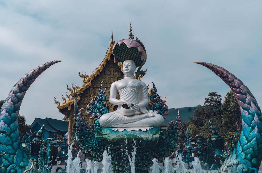 Una estatua de un Buda sentado frente a una fuente