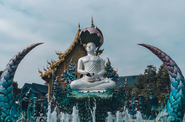A statue of a buddha sitting in front of a fountain — Chiang Rai, Thailand