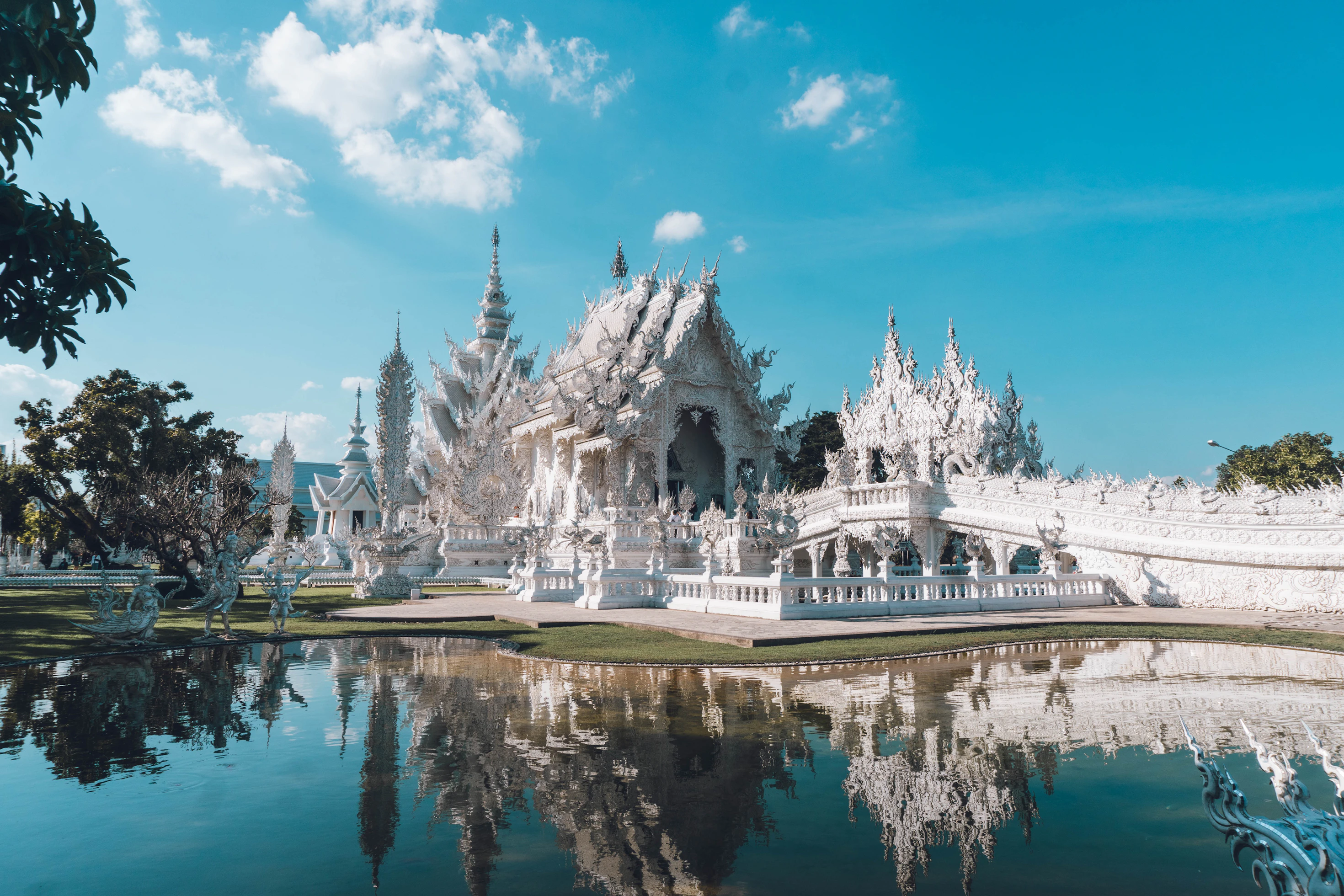 Der Weiße Tempel Wat Rong Khun bei Chiang Rai mit Spiegelung im Wasserbecken