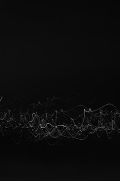 A series of thin, white lines create a chaotic, wave-like pattern against a solid black background. The lines intertwine and overlap, resembling an abstract visualization of sound waves or light trails.