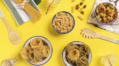 three bowls of pasta sit on a yellow surface