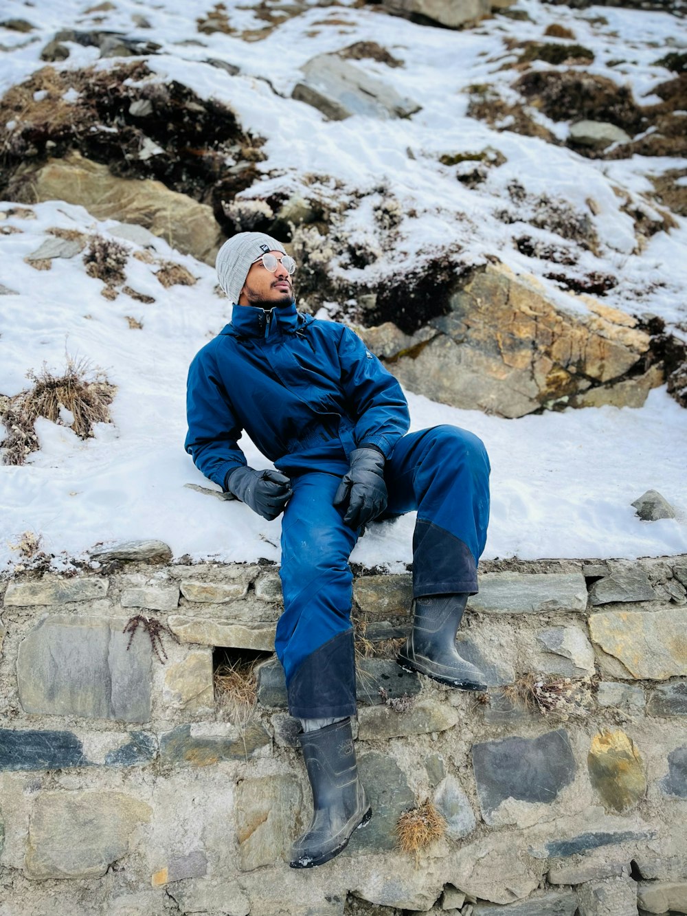 Ein Mann sitzt auf einer Steinmauer im Schnee