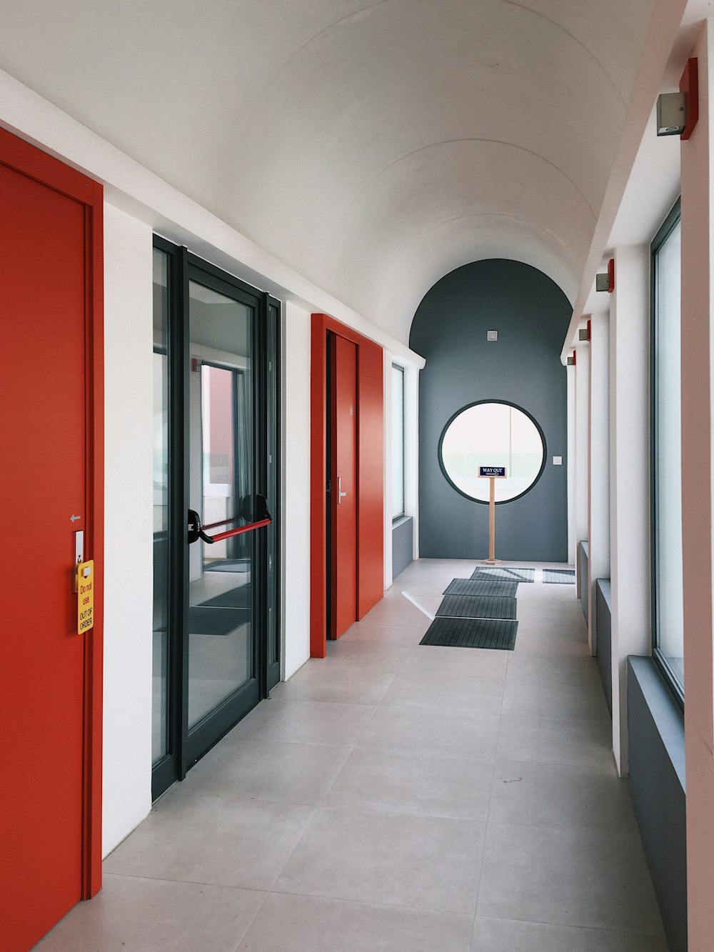 a hallway with red and white doors and a round window