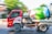 A red cement mixer truck is moving along a road. The truck has an eagle design on the side, and the drum is painted with colorful flowers and nature motifs. The background shows green foliage and blurred motion, indicating the vehicle is in motion.
