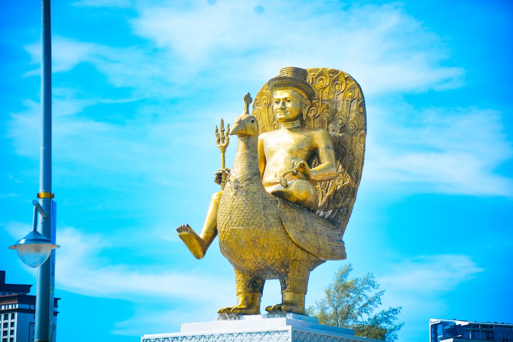 a golden statue of a person holding a bird