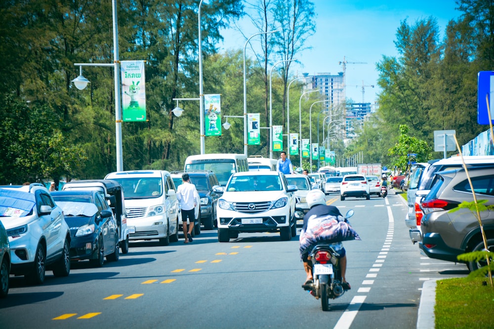 a man riding a motorcycle down a street next to a bunch of cars