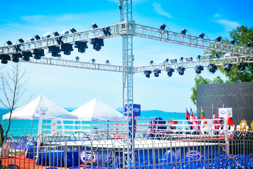 A stage and lighting rig being built on a beach