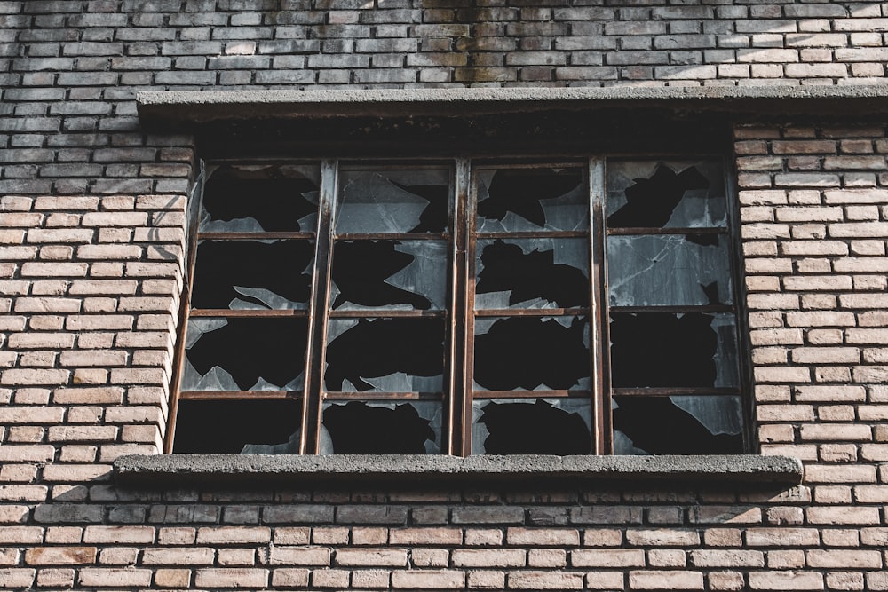 a broken window on a brick building with broken glass