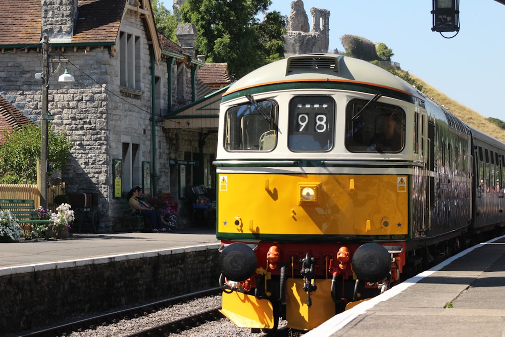 a yellow and green train pulling into a train station