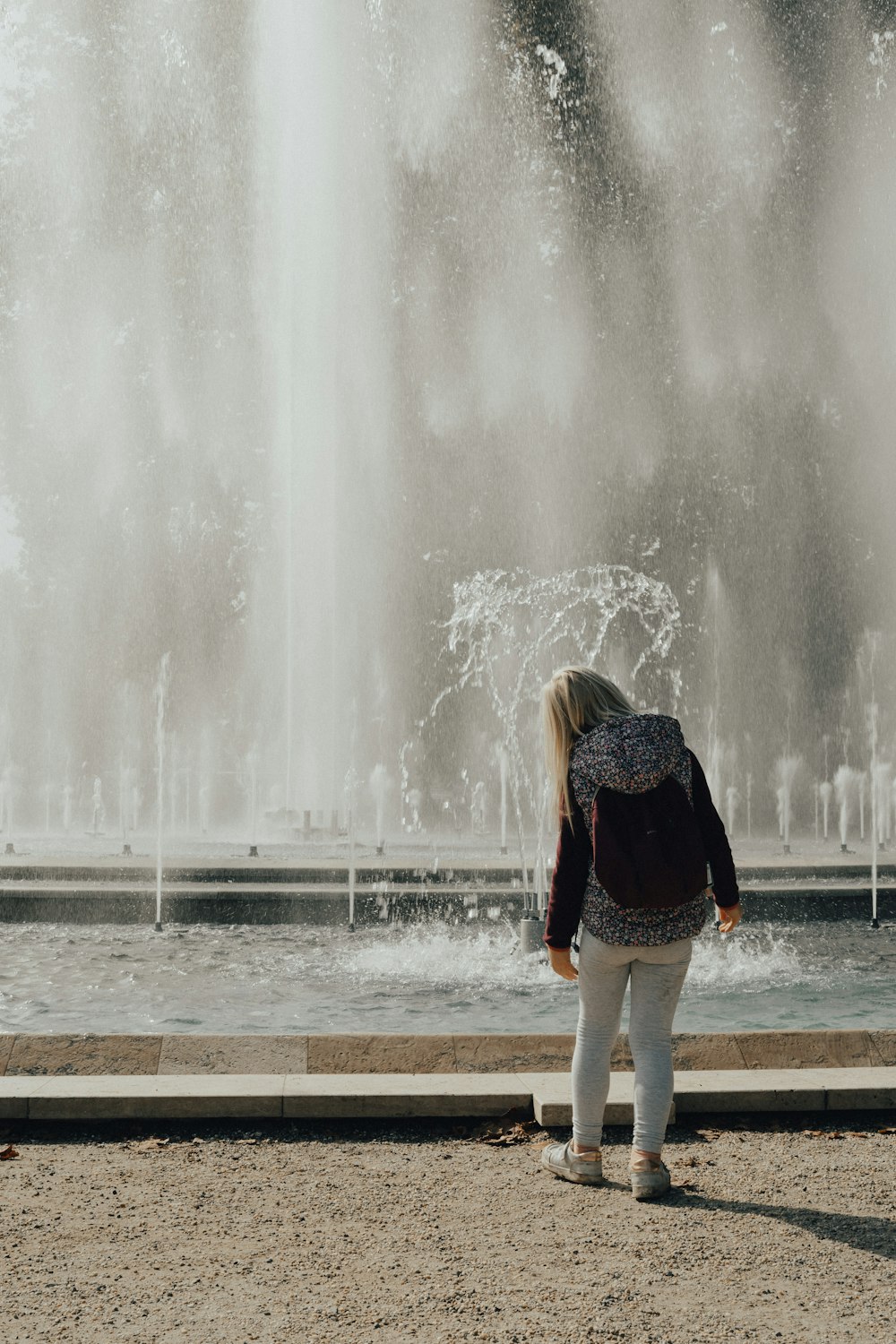 a woman standing in front of a water fountain