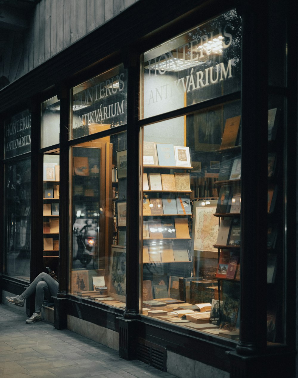 a person sitting on the sidewalk in front of a store