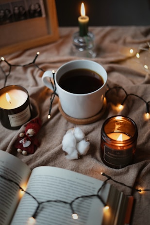 A cozy corner with a latte-scented candle glowing softly beside a steaming cup of coffee.