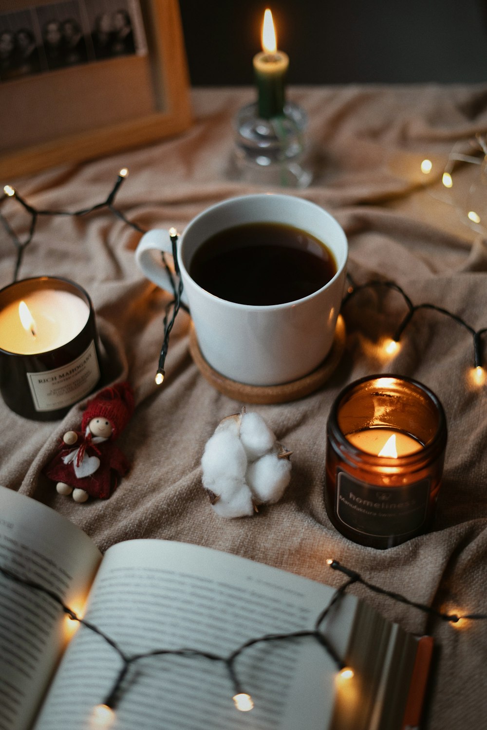 a cup of coffee next to a candle and a book