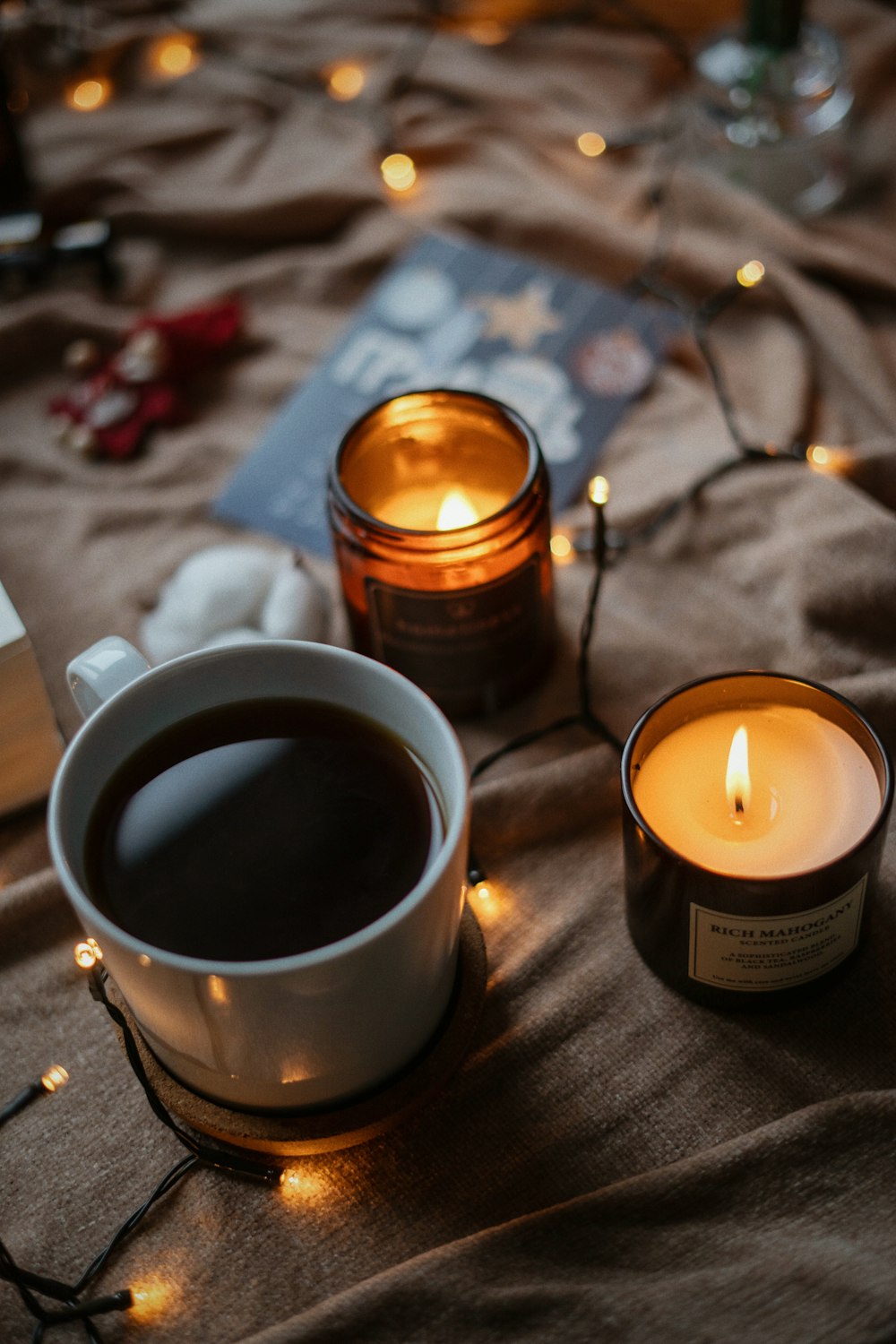 a cup of coffee next to a lit candle