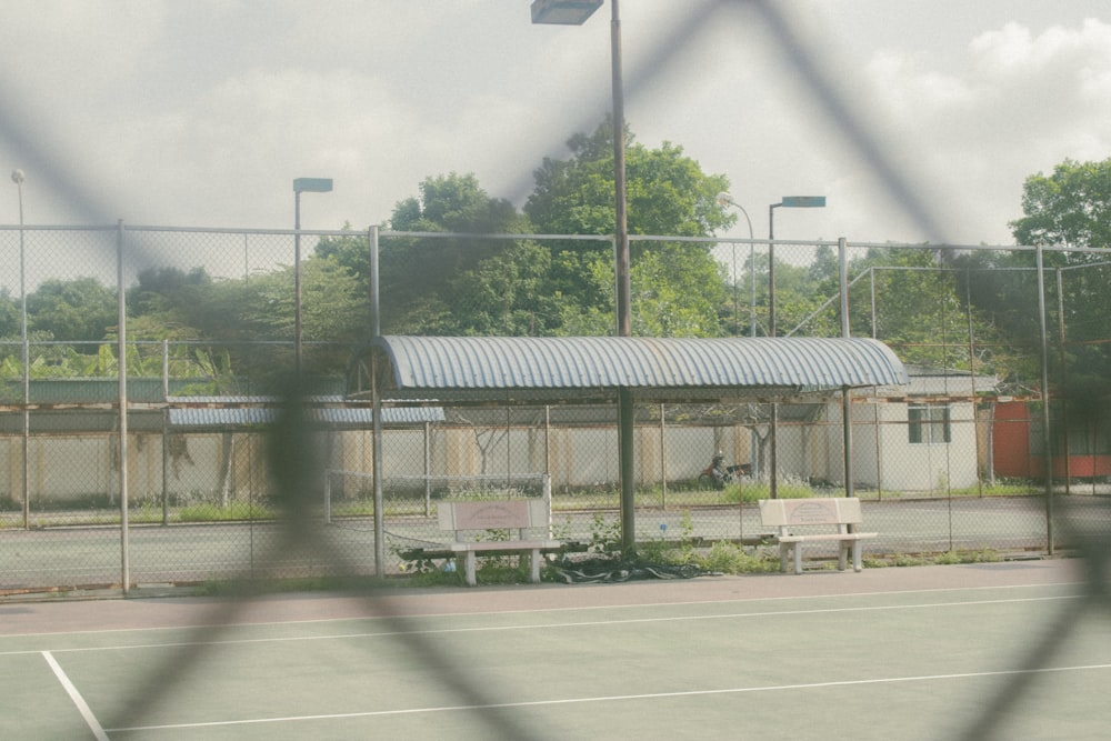 a tennis court with a bench behind a chain link fence