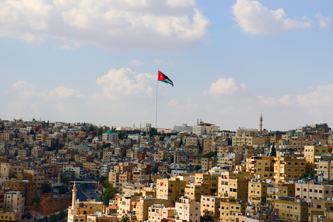 a flag flying in the sky over a city, Amman