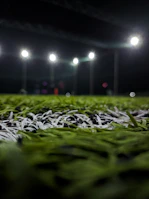 Close-up of a football spinning on lush green grass under bright stadium lights