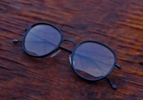 Close-up of a pair of modern eyeglasses resting on a wooden counter.