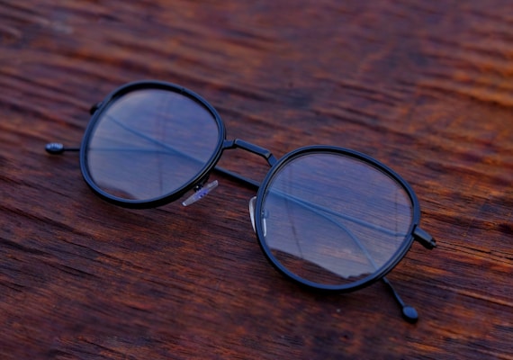 A close-up of stylish eyeglasses displayed on a wooden table.