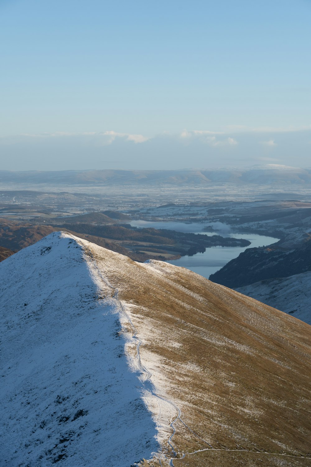 a snow covered hill with a lake in the distance