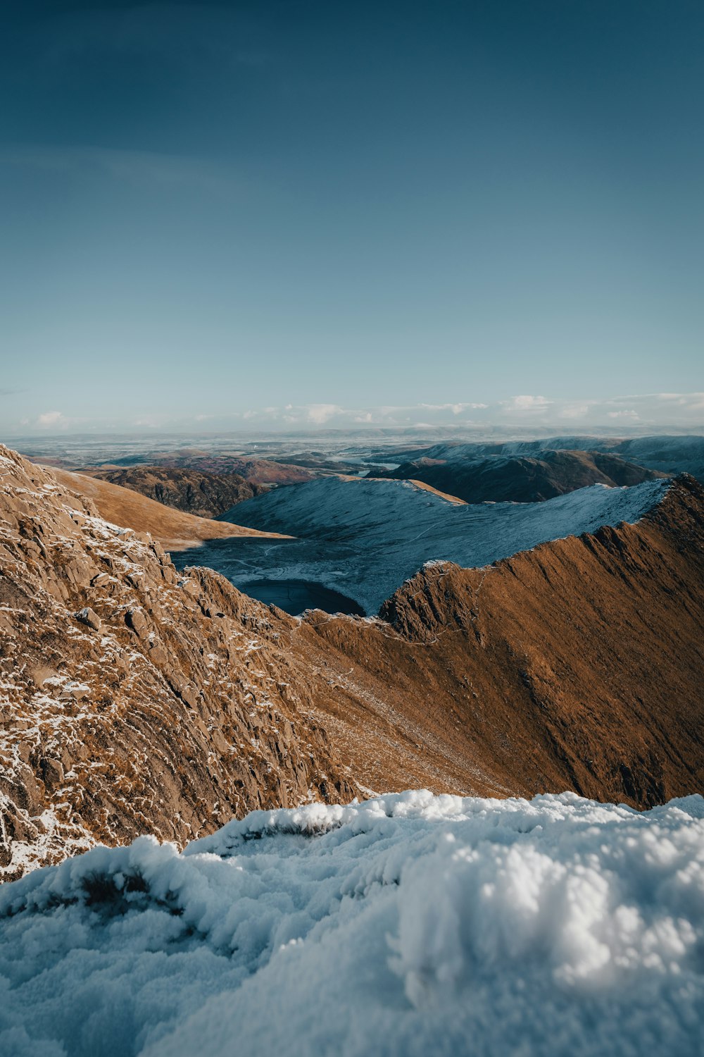 a snow covered mountain with a lake in the distance