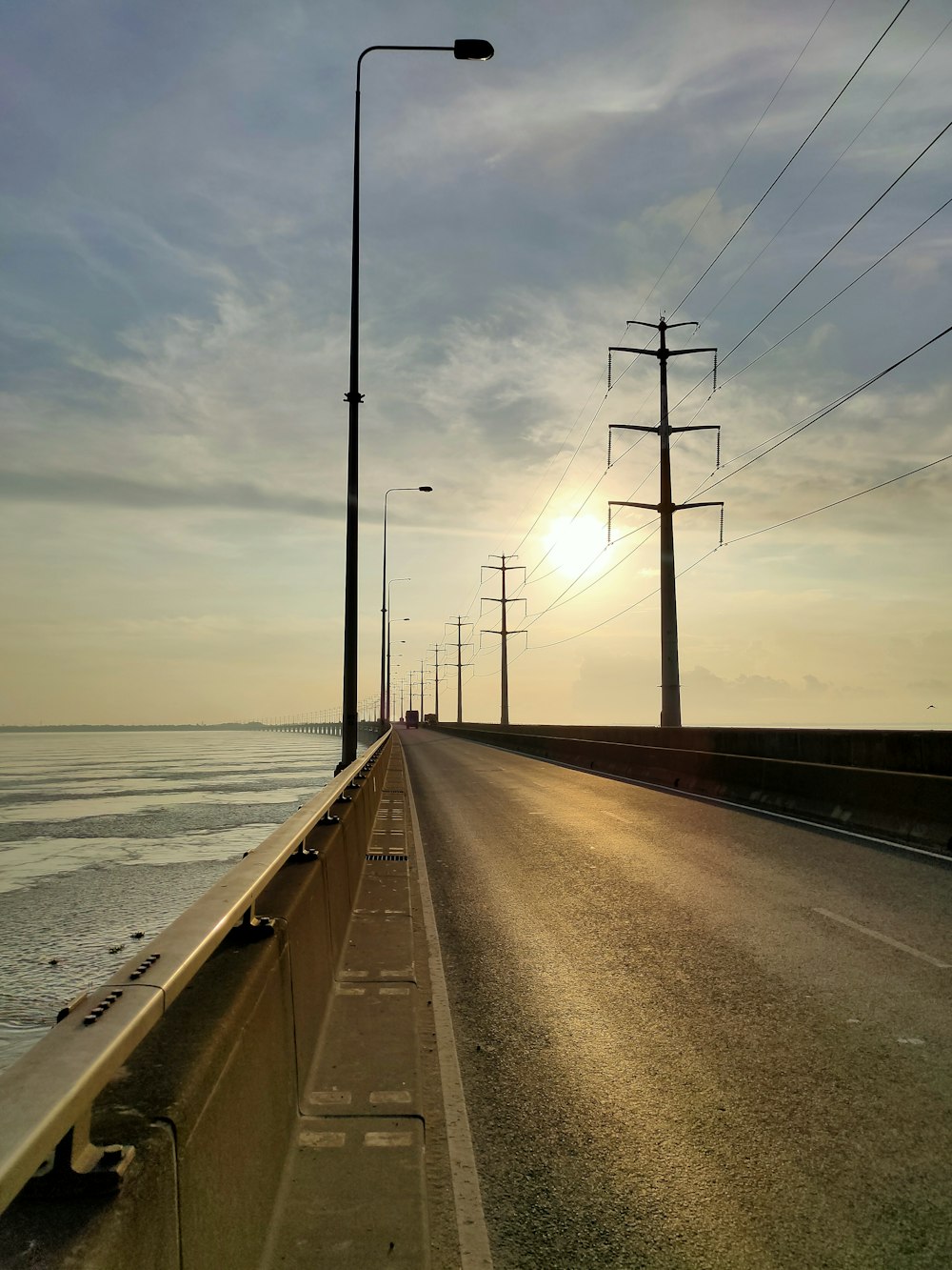 the sun is setting over the ocean on the road