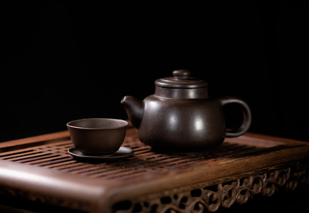 a tea pot and a cup on a wooden tray