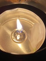 A close-up of a beautifully crafted candle holder with a flickering candle inside, surrounded by delicate artificial plants.