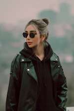 Close-up of a model wearing a sleek black oversized hoodie with electric blue accents, standing against a stark urban backdrop.