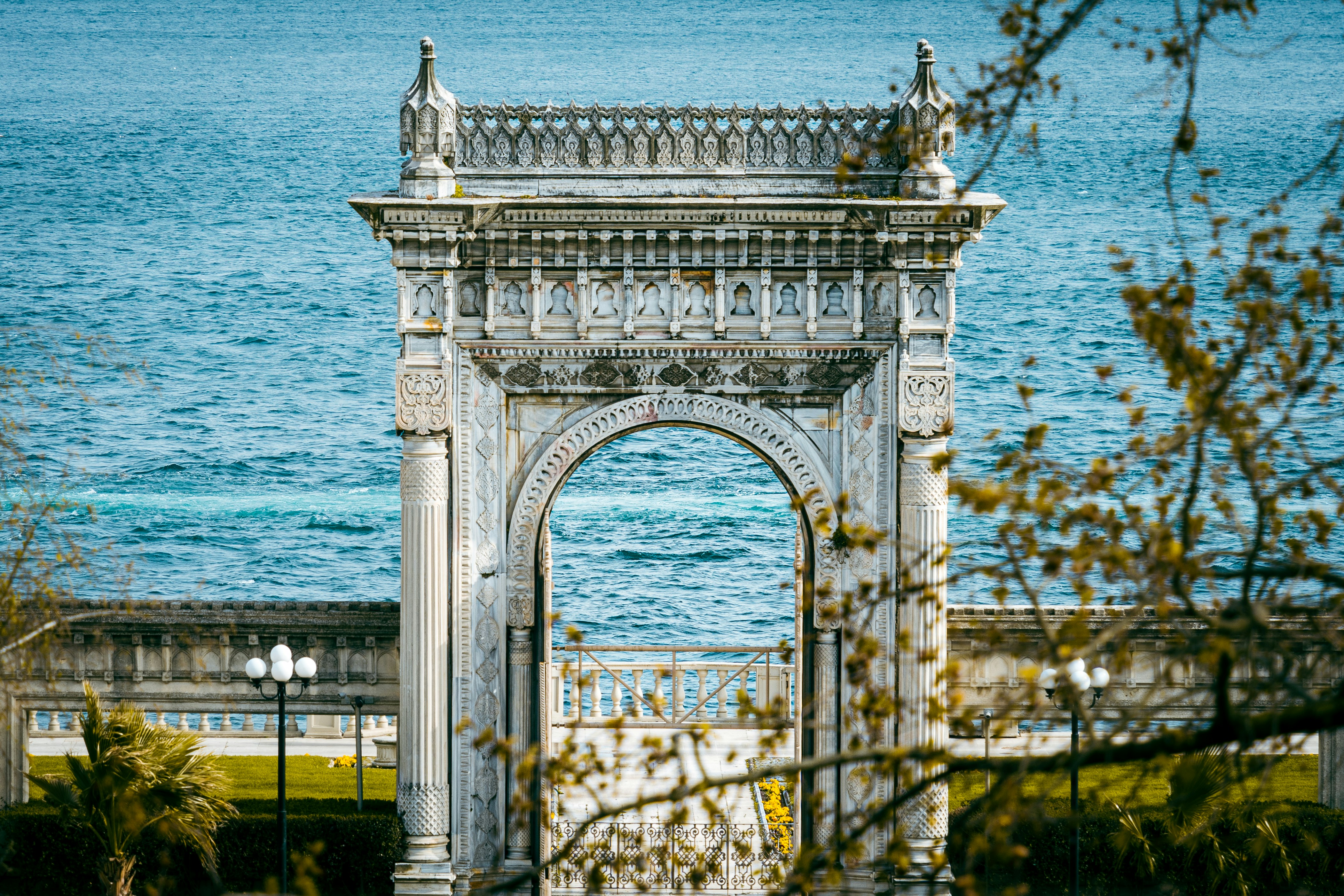 a large white archway in front of a body of water