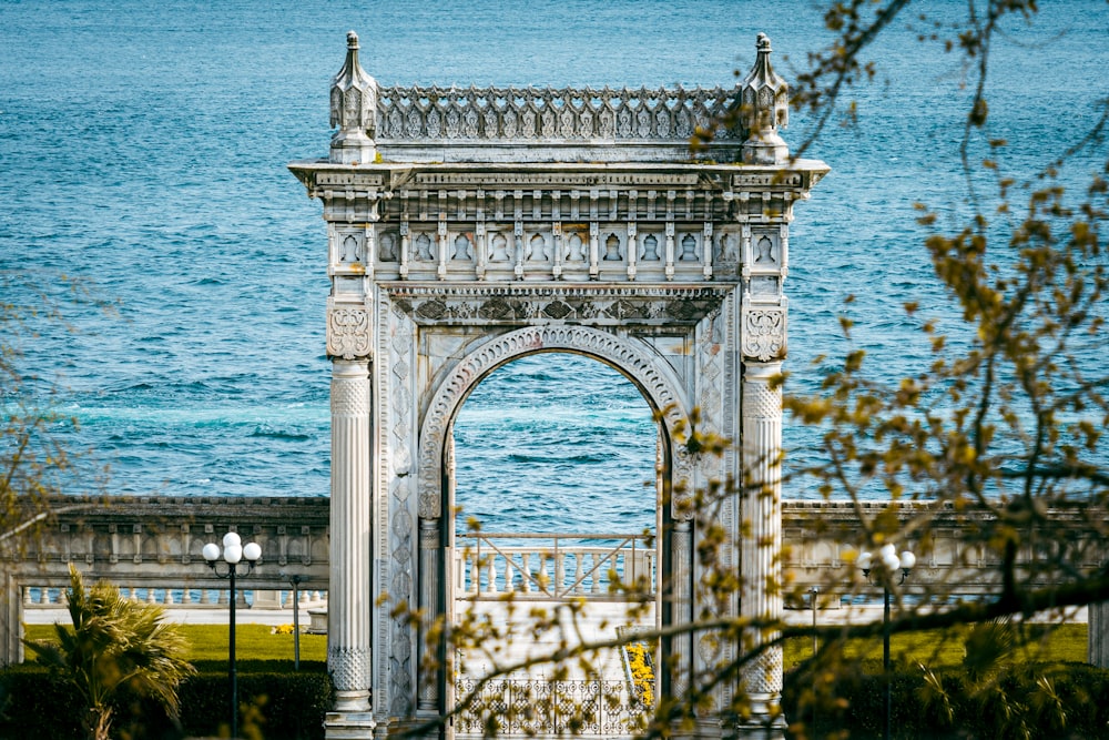 a large white archway in front of a body of water