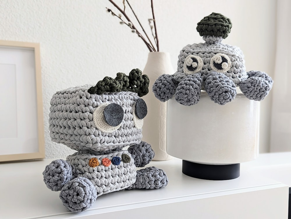 a crocheted stuffed animal next to a crocheted vase
