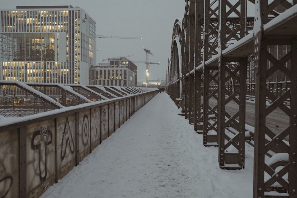 a bridge that is covered in snow with buildings in the background
