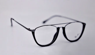 Close-up of premium designer eyeglasses displayed on a sleek white surface.