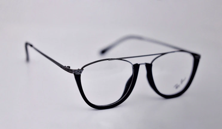 A sleek black pair of glasses with subtle metallic accents showcased against a minimalist white background.