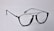 A pair of black-rimmed eyeglasses with a sleek and modern design. The glasses are placed on a plain light background, highlighting their stylish shape and glossy finish.