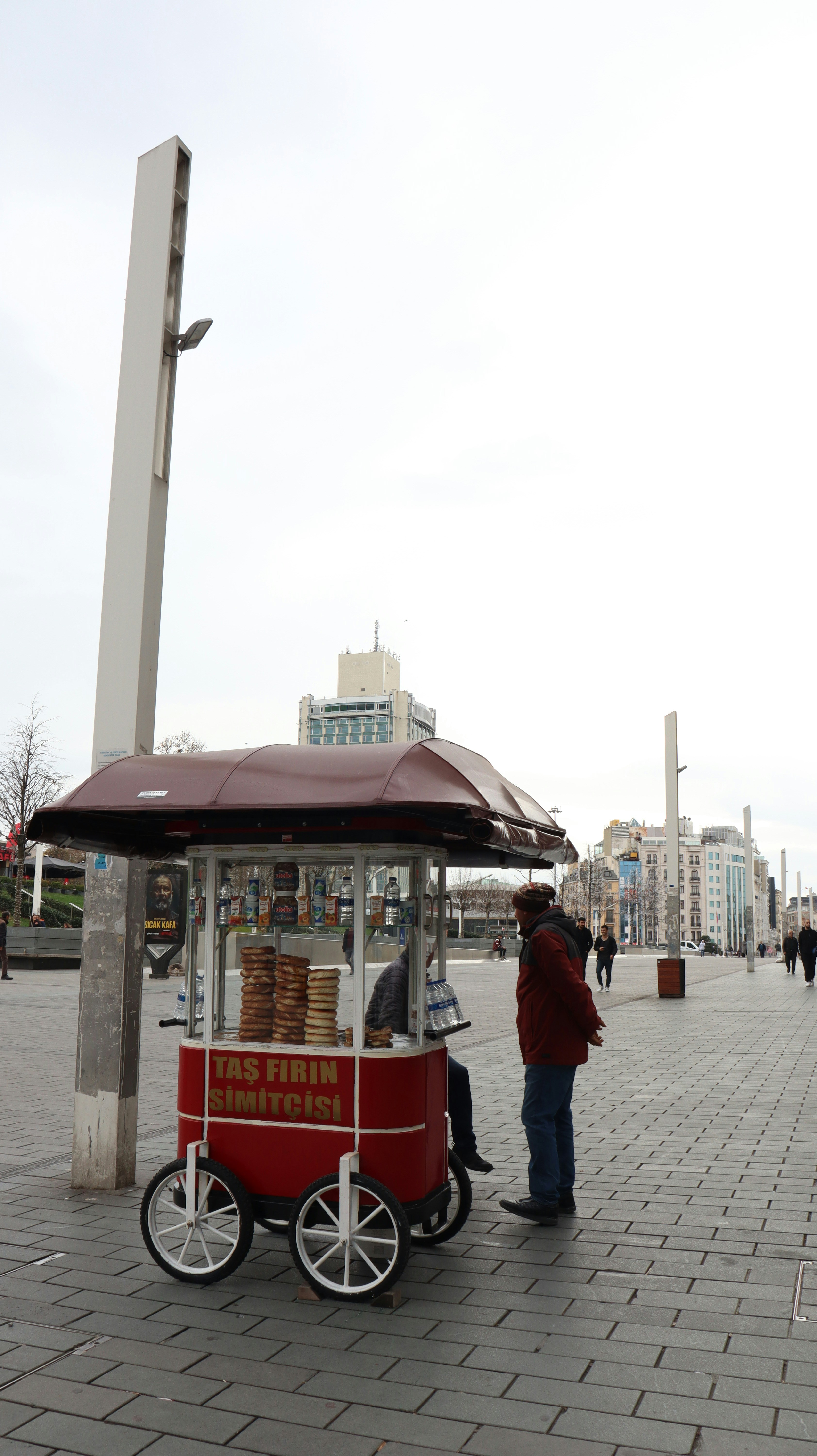 Un hombre parado junto a un carrito de comida en una acera