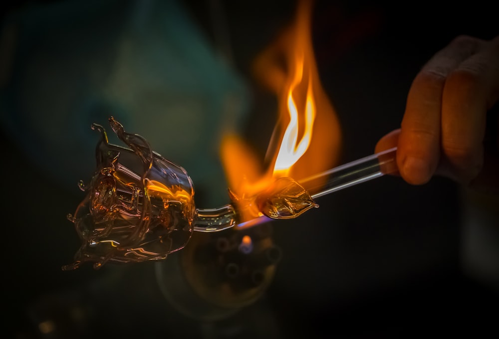 a person holding a glass with a flame inside of it
