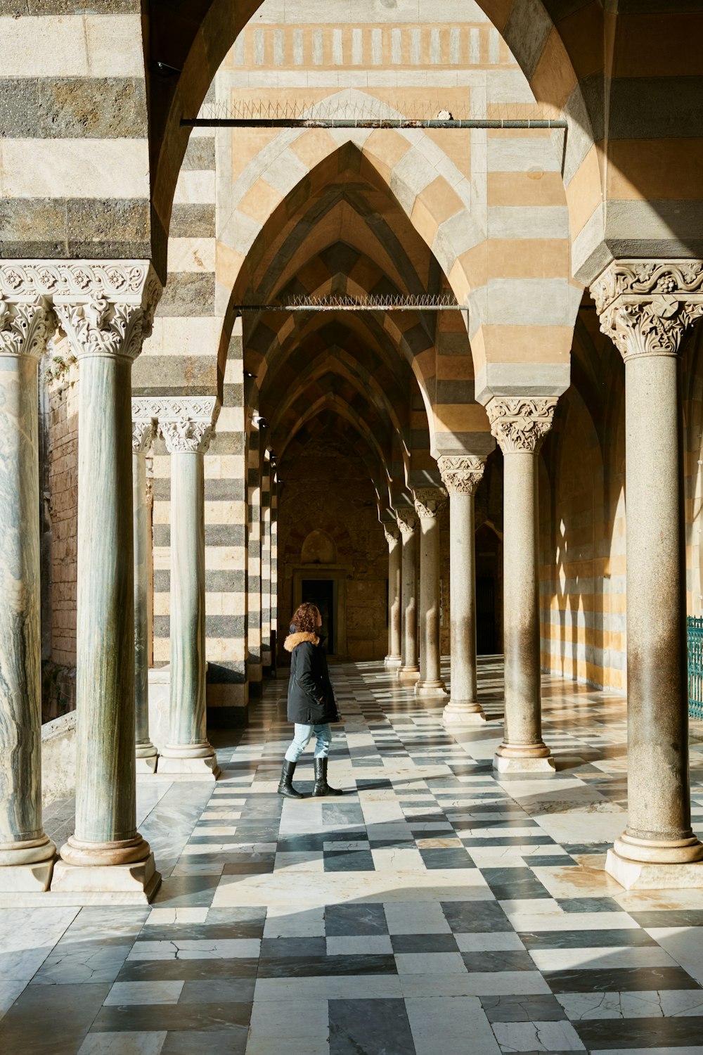 a woman standing in a hallway between two pillars
