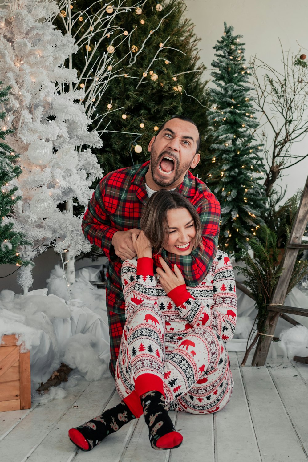 a man and a woman sitting in front of a christmas tree