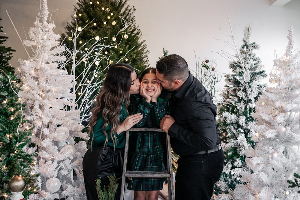 a couple of people that are standing in front of a christmas tree