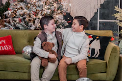 a boy and a boy sitting on a couch with a teddy bear
