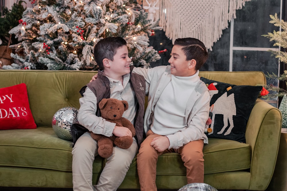 a boy and a boy sitting on a couch with a teddy bear