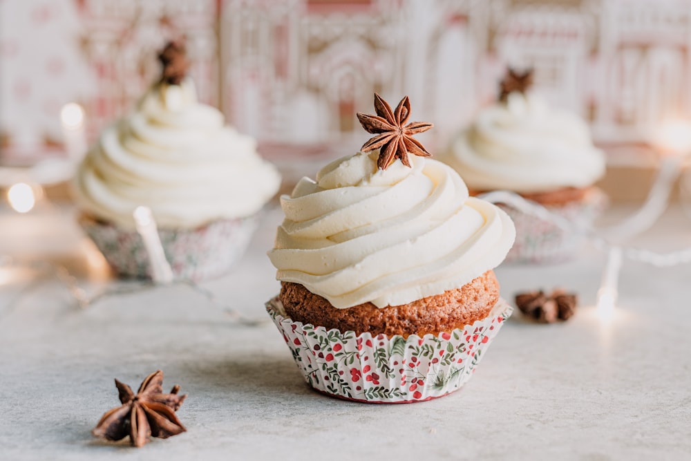 three cupcakes with white frosting and cinnamon stars on top