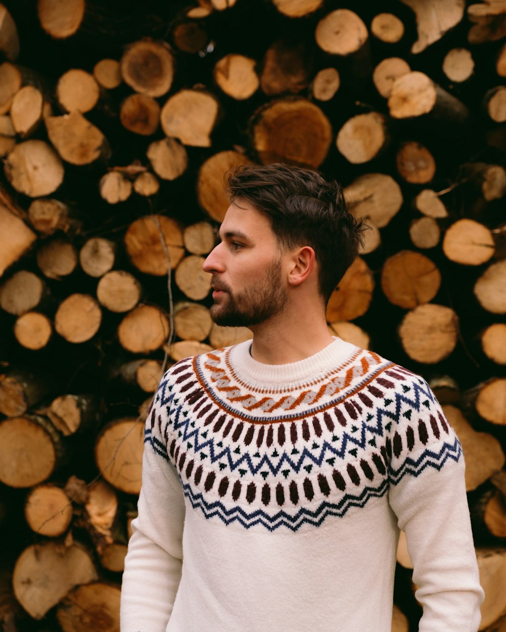 a man standing in front of a pile of logs